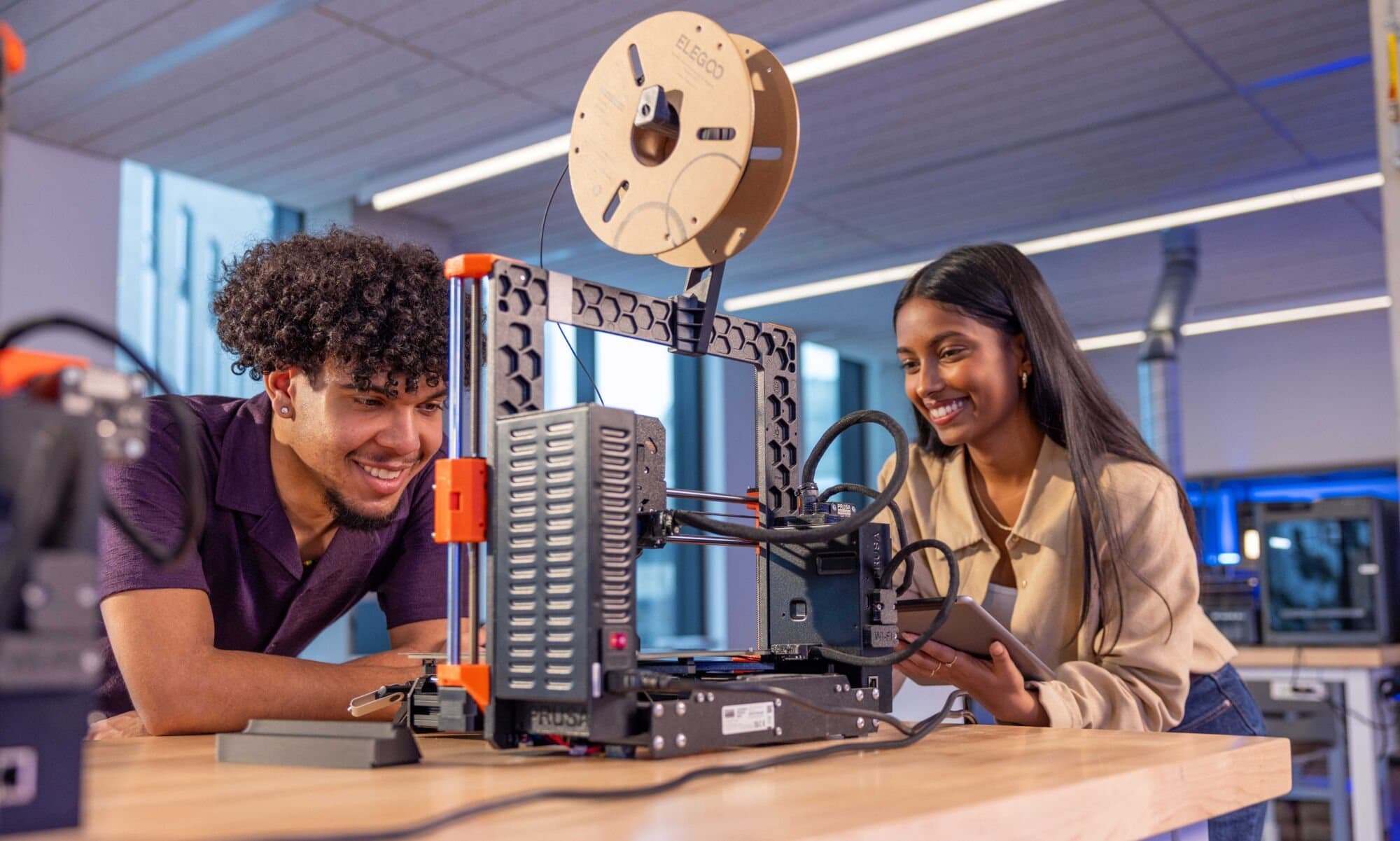 Kalan Roye and Aditi Basdeo watching a Prusa 3D printer in Western University's digital makerspace