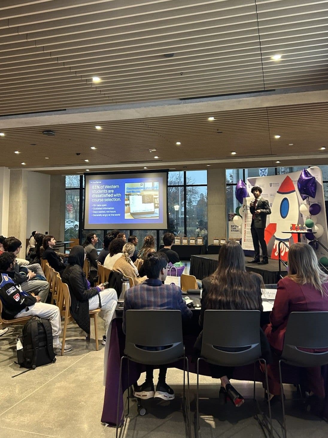 Kalan Roye pitching Crux Planner on stage at the Western Morrissette Institute Startup Challenge in front of a crowd and judges